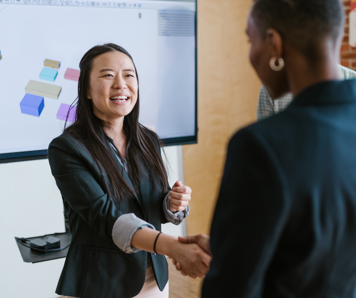 Two business professionals shaking hands representing a successful customer journey conversion after closing gaps in the sales process